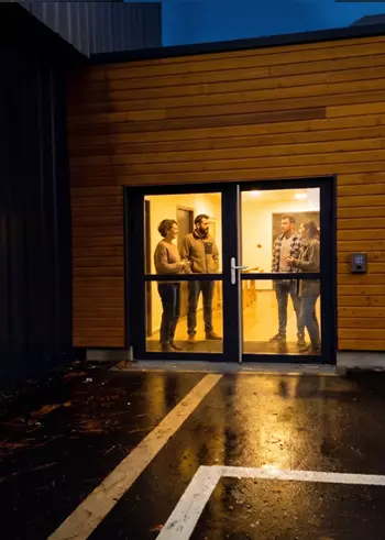 Bâtiment municipal éclairé la nuit avec lecteur de contrôle d'accès MGP Matic à l'entrée, vue rapprochée